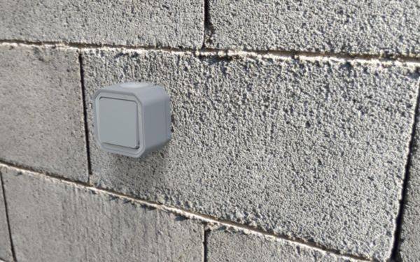 Un interrupteur gris est installé sur un mur en béton gris.