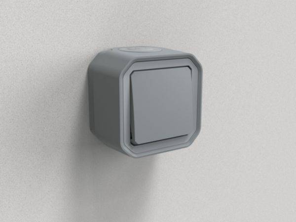 Un interrupteur gris au design minimaliste est monté sur un mur gris clair.