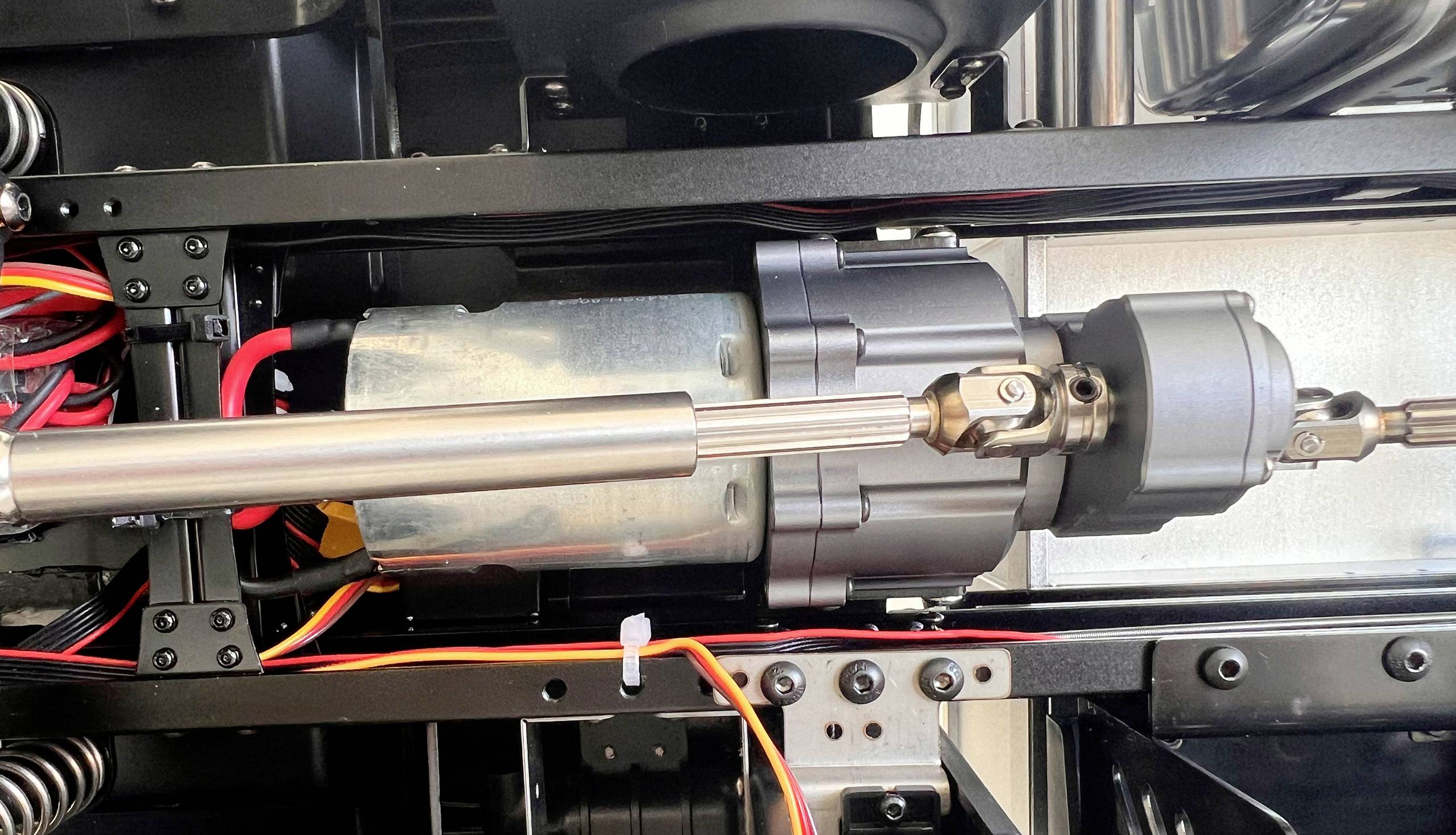 Un moteur électrique dans un dispositif technique, entouré de câbles et de composants métalliques, visible dans un gros plan.