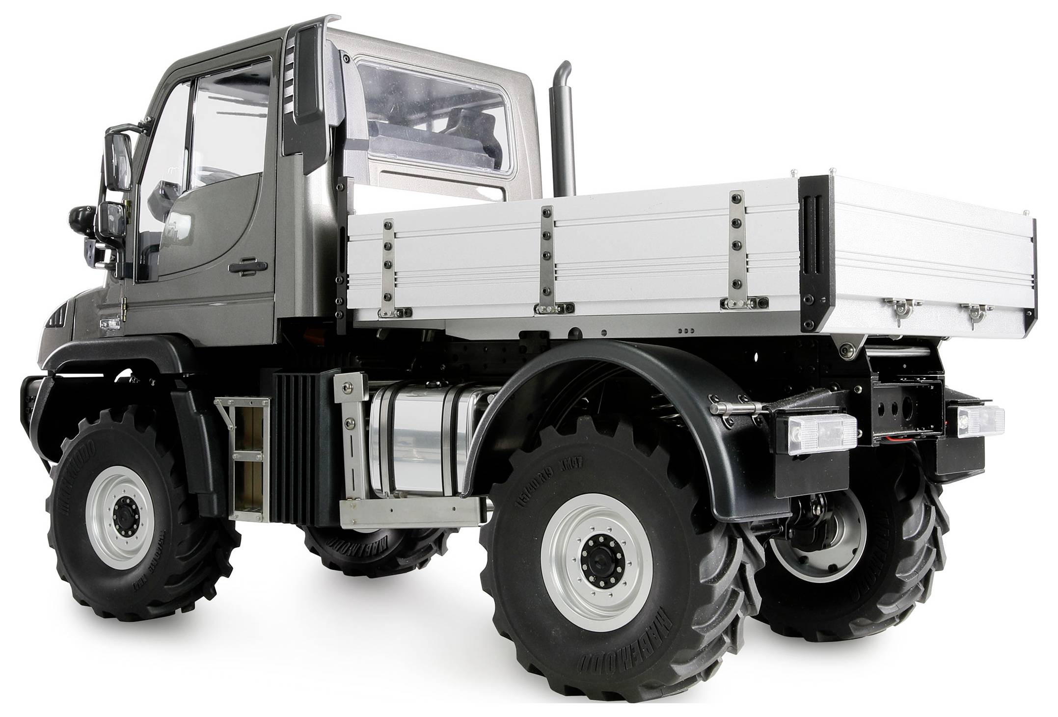 Un camion argenté avec un grand dégagement au sol et des pneus robustes, adapté aux terrains difficiles. Vue latérale montrant la surface de chargement.