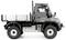 Camion gris avec une petite surface de chargement et de grandes roues, vue latérale. Le véhicule est haut, robustement construit et adapté aux terrains accidentés.