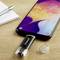 Un smartphone est posé sur une table, connecté à une clé USB Intenso. À côté se trouve un bloc-notes avec un stylo à bille.