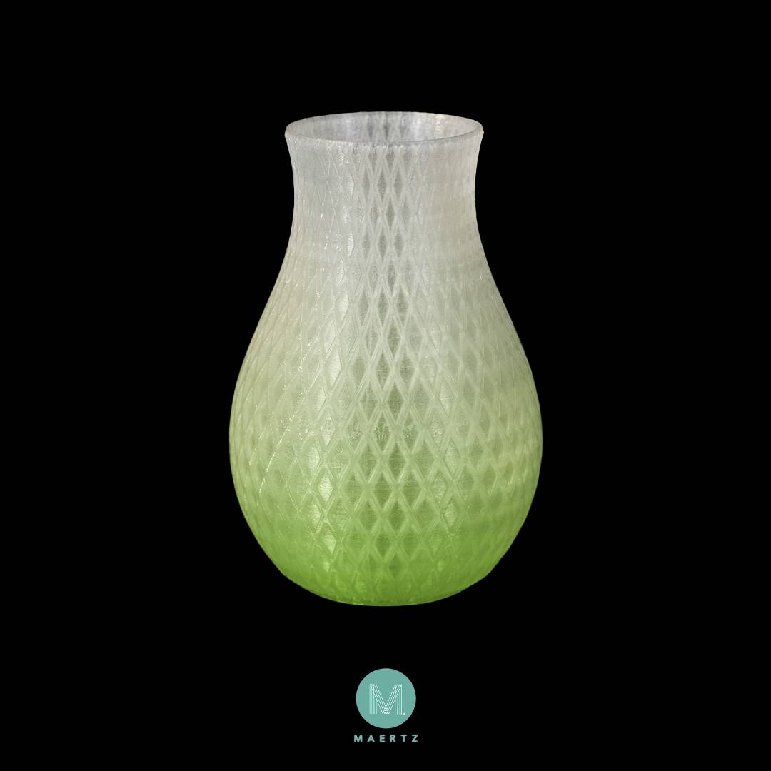 Un vase à motifs en losanges, blanc dans la partie supérieure et vert dans la partie inférieure, sur un fond noir.