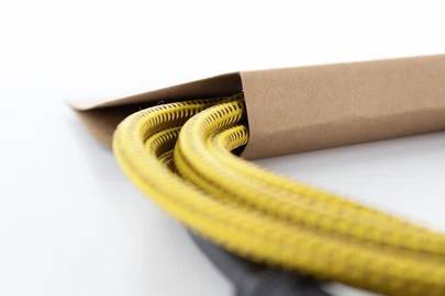 Câble jaune, partiellement sorti d'un emballage en papier brun, sur un fond blanc.