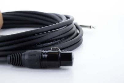 'Gros plan d'un câble audio enroulé sur une table, avec une fiche XLR au premier plan.'