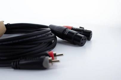 Câble audio noir avec connecteur XLR et raccords RCA sur fond blanc, pour des connexions audio professionnelles.