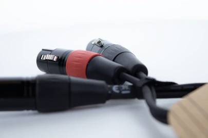 Trois câbles audio avec connecteurs XLR sont posés côte à côte sur une surface blanche. L'un des câbles a un anneau rouge.