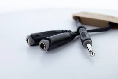 Séparateur de câble audio avec deux connecteurs femelles et un connecteur mâle sur fond blanc.