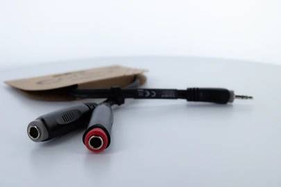 Un câble répartiteur audio avec deux fiches femelles et une fiche mâle sur un fond blanc.