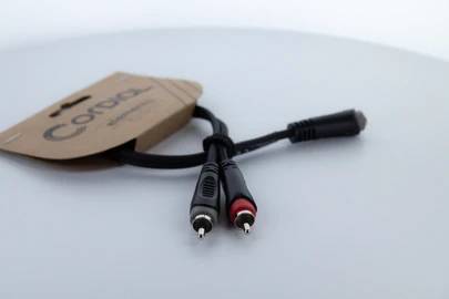 Un câble audio avec deux fiches RCA et une fiche jack, fixé sur une étiquette en carton portant l'inscription 'Cordial'.