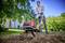 Un homme utilise un cultivateur de jardin électrique sur une pelouse verte devant une maison, portant des lunettes de protection et des gants.