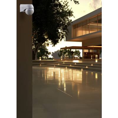 Villa moderne avec grande piscine au coucher du soleil, entourée d'arbres et d'un éclairage élégant.