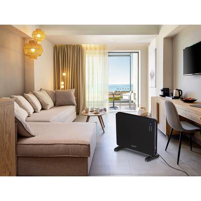 Un salon moderne avec un canapé, une table basse et une grande fenêtre offrant une vue sur la mer. Un appareil de chauffage est posé sur le sol.