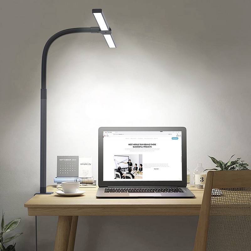 Un ordinateur portable posé sur un bureau affiche une page web ouverte. À côté, on trouve une tasse, des livres et une lampe de bureau qui brille intensément.