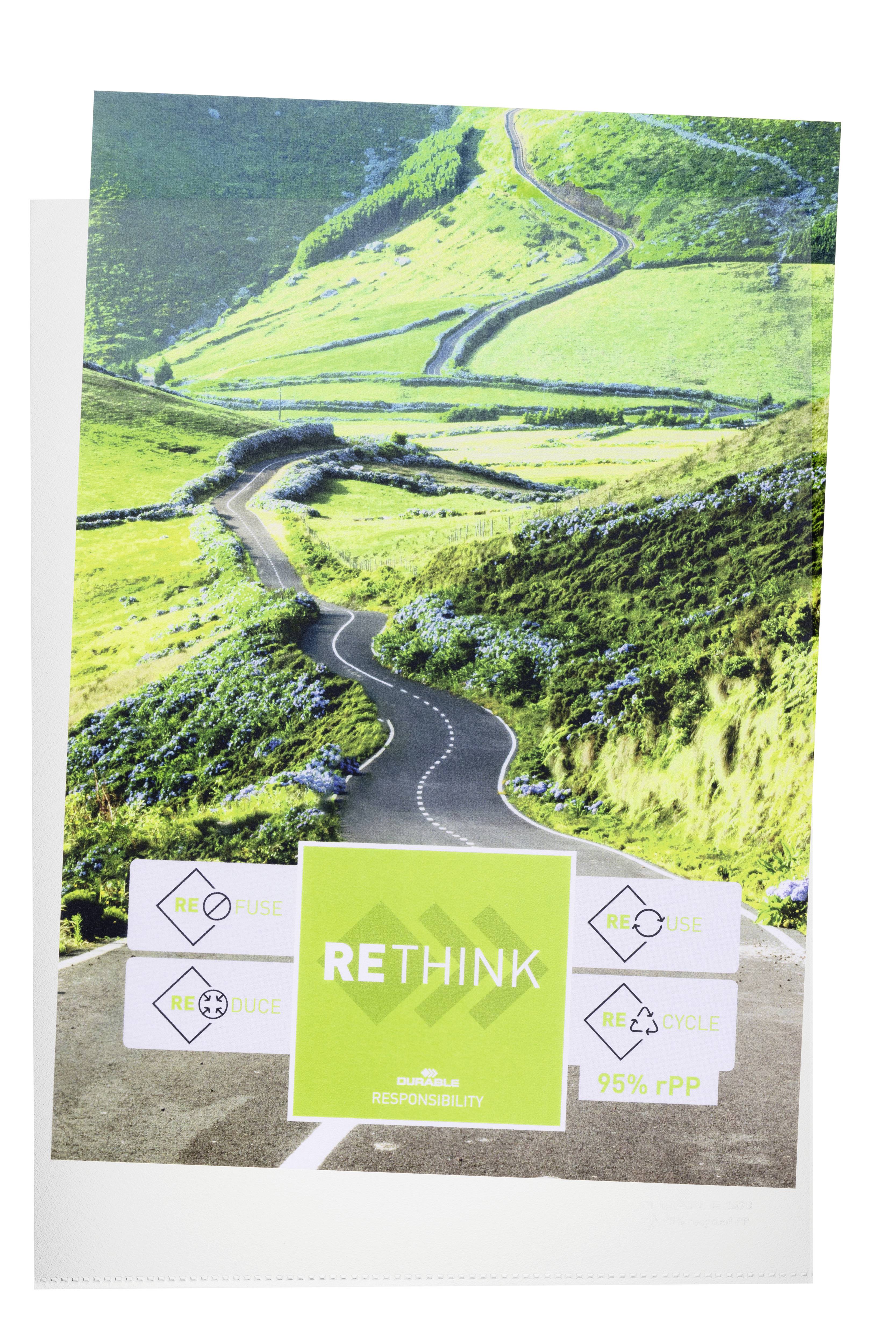 Une route sinueuse serpente à travers des collines verdoyantes. Au premier plan, un panneau portant l'inscription 'RETHINK', entouré de symboles de recyclage.