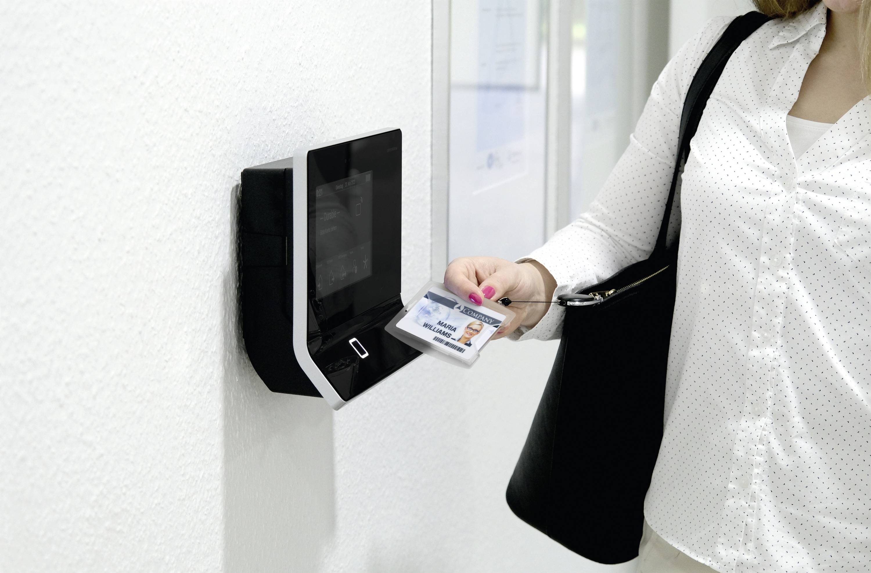Une personne passe une carte d'accès près d'un lecteur électronique fixé au mur pour entrer dans une zone sécurisée.