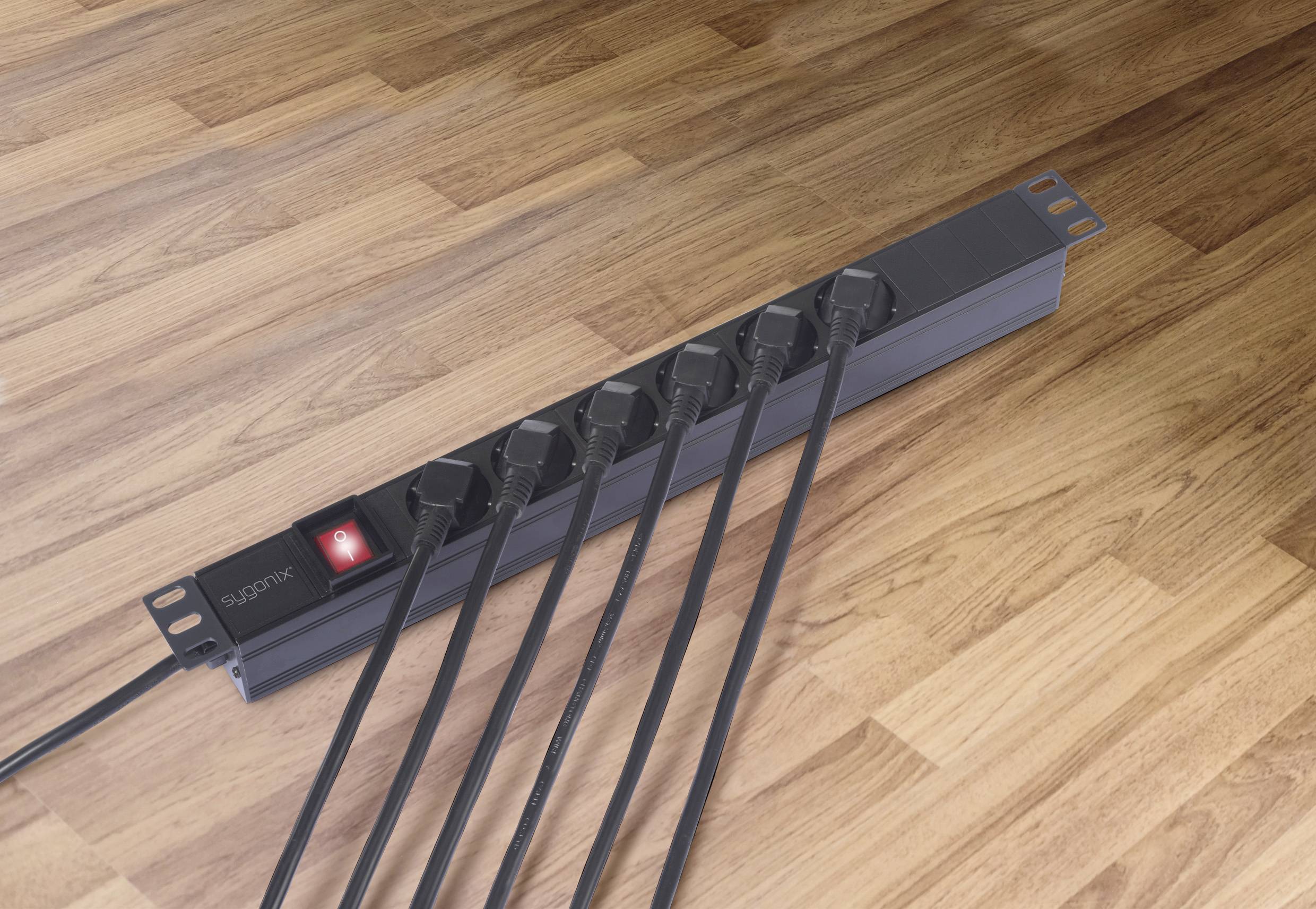 Bloc multiprises à six prises occupées sur un sol en bois, l'interrupteur rouge est allumé.