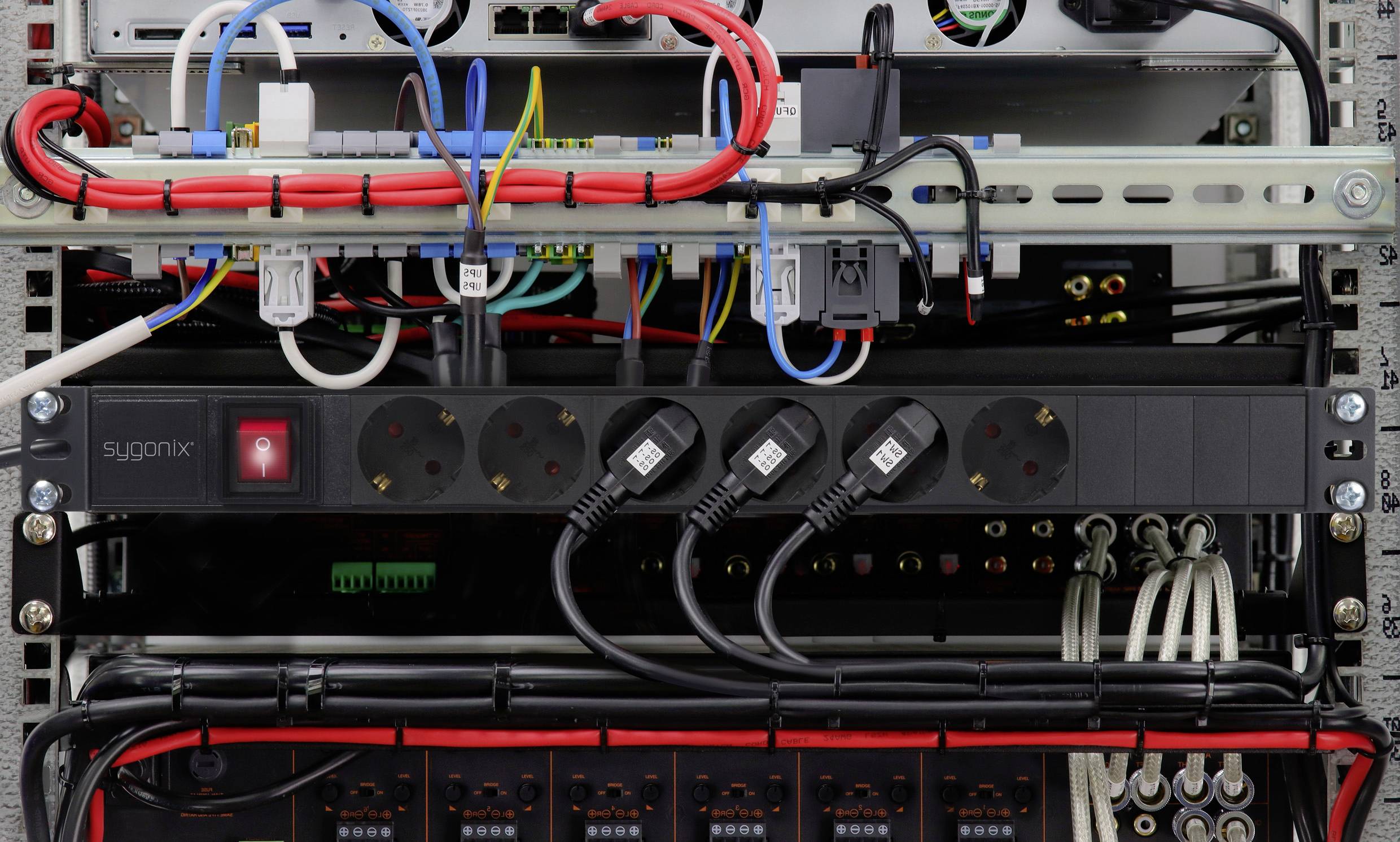 Une armoire électrique ouverte montre plusieurs câbles et appareils connectés. Différentes lignes électriques et distributions sont visibles.