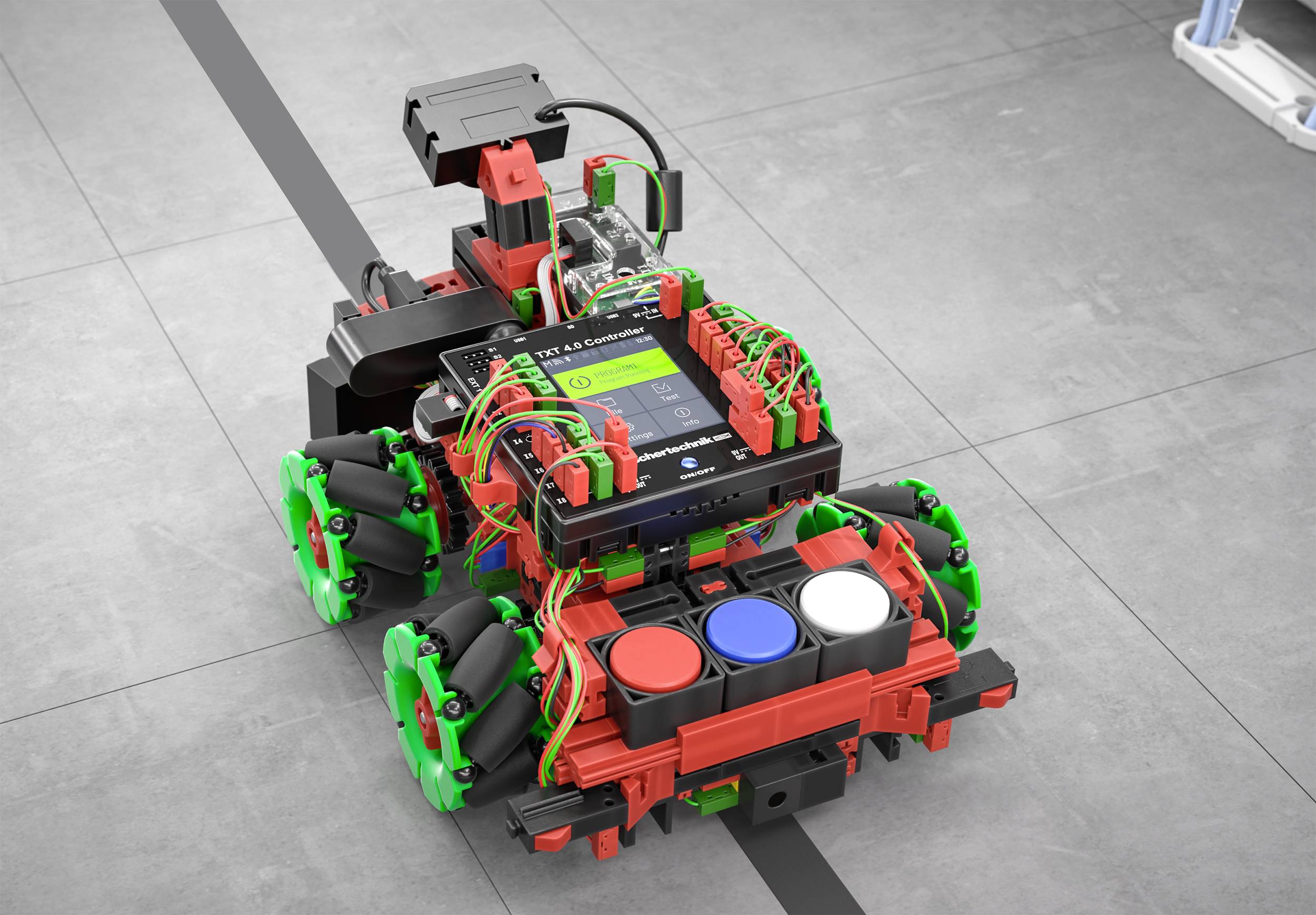 Un petit robot sur un revêtement de sol se déplace le long d'une ligne noire. Il est équipé de roues colorées et affiche un écran numérique.