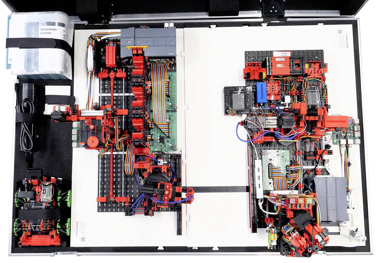 Une boîte de connexion ouverte révèle une disposition complexe de composants électroniques rouges et noirs et de câbles multicolores.