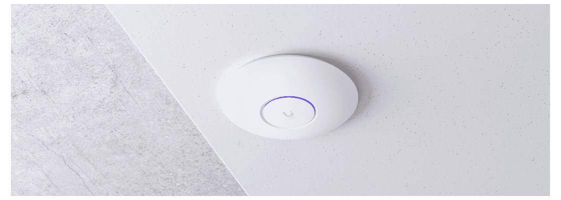 Un dispositif circulaire blanc monté au plafond, doté d'un anneau bleu lumineux, probablement un détecteur de fumée ou un point d'accès sans fil, fixé à un plafond gris clair.