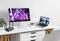 Un bureau moderne avec un moniteur affichant un spectacle de scène coloré, un ordinateur portable avec un écran représentant un paysage naturel, un clavier et un routeur.