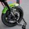 Une moto verte avec un système de freinage puissant est immobile. Un solide antivol sécurise la roue avant sur un trottoir.