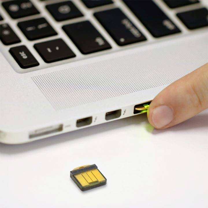Une main insère une clé USB dans un ordinateur portable. Un adaptateur de carte SD est posé à côté.