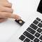 Une main insère une clé USB dans un ordinateur portable. La clé USB porte un symbole jaune.