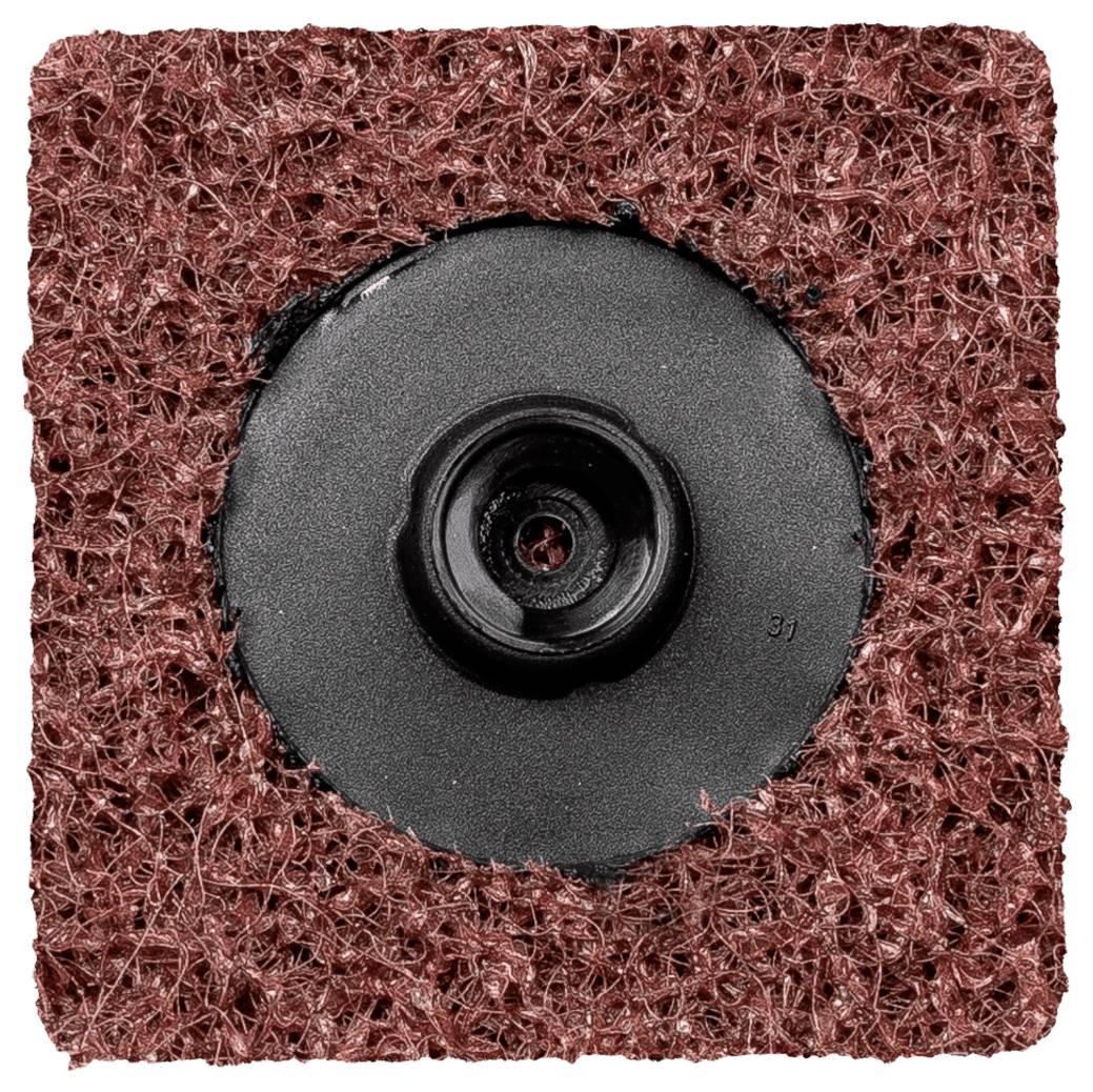 Gros plan sur un disque abrasif rouge avec un centre de fixation noir, utilisé pour le traitement des surfaces et le nettoyage dans les travaux artisanaux.