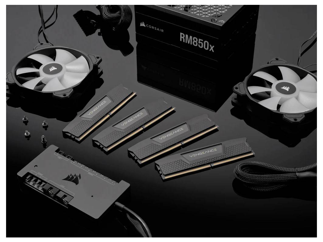 'Ensemble de matériel informatique : Deux ventilateurs, quatre modules de RAM, une alimentation RM850x et d'autres composants sur fond noir.'