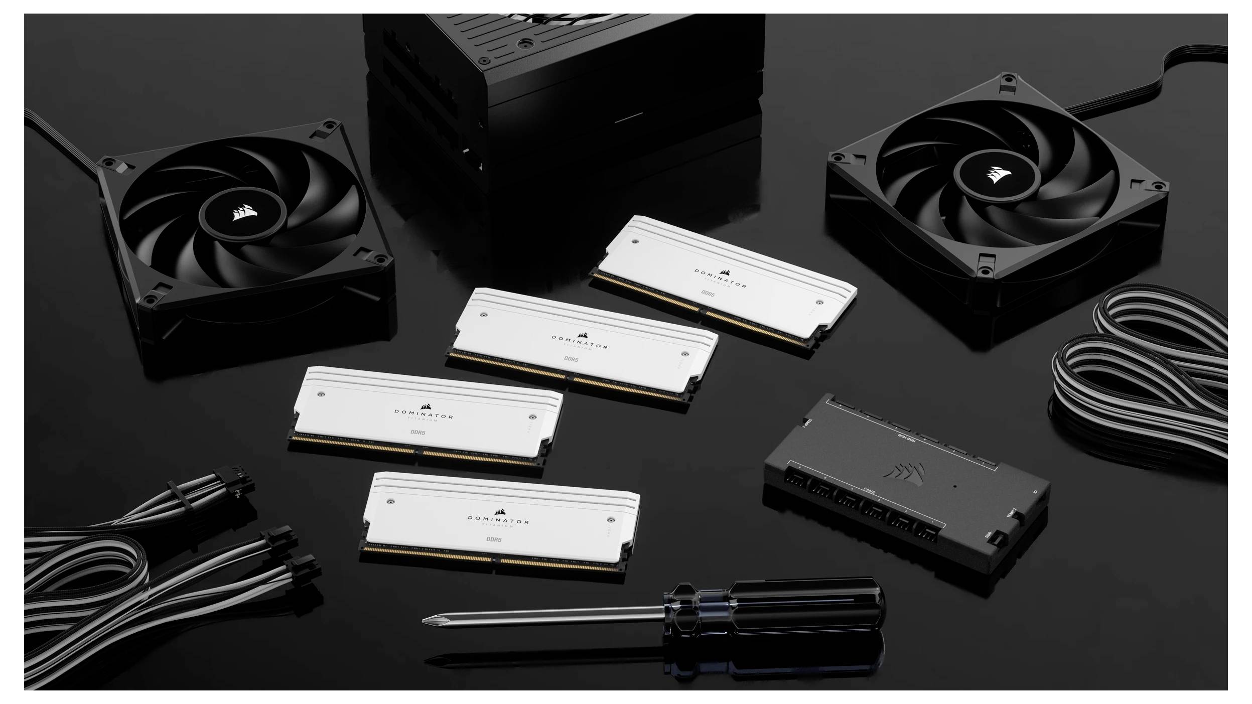 Plusieurs composants de matériel informatique, dont des ventilateurs, des modules de RAM, des câbles et un tournevis, posés sur une surface noire.