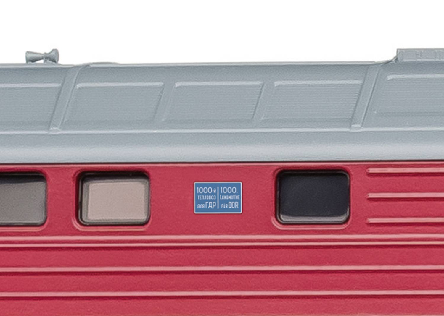 Gros plan d'un wagon de train rouge avec un bouclier bleu et des fenêtres. L'image montre les détails d'une façade de train moderne.