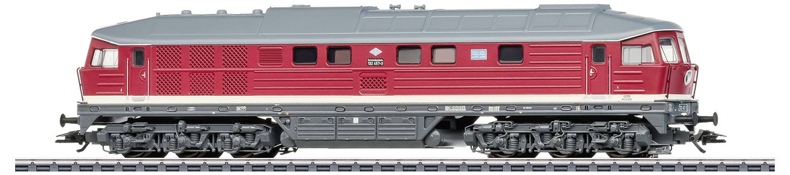 Une locomotive-modèle rouge avec un toit gris sur une voie ferrée. Elle présente des détails tels que des fenêtres, des grilles de ventilation et l'emblème d'un fabricant.
