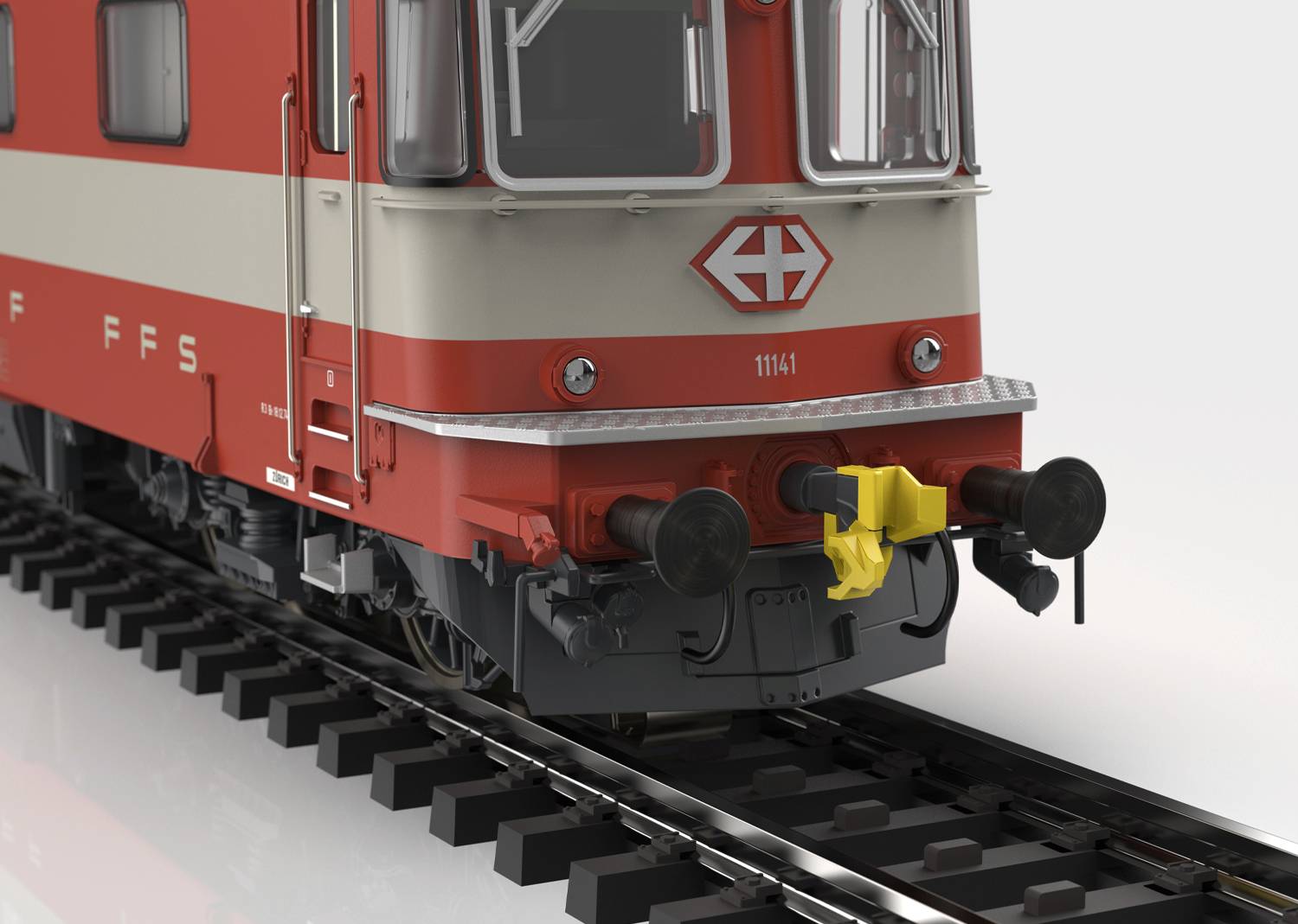 Gros plan sur une locomotive rouge et crème avec le logo suisse, stationnée sur des rails, vue de face.