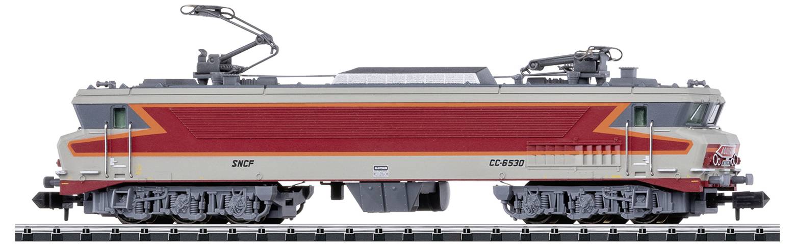 Locomotive de train miniature en vue latérale, grise et rouge, avec des détails visibles des roues et des caténaires sur les rails.