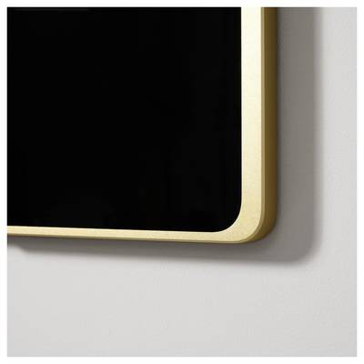 Un miroir rectangulaire encadré d'or est accroché à un mur. Seul le bord et une petite partie de la surface du miroir sont visibles.