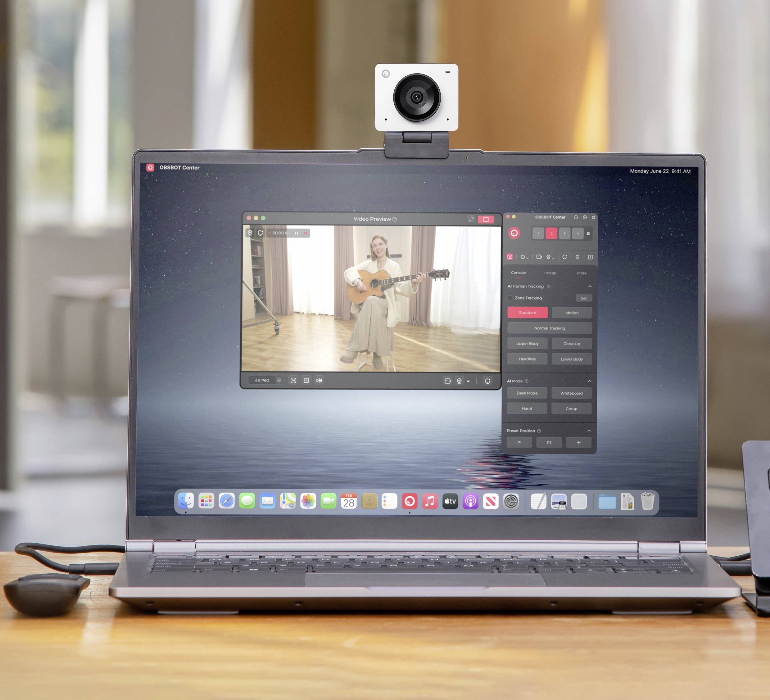 Un ordinateur portable affiche un enregistrement vidéo d'une personne jouant de la guitare. Une caméra est installée au-dessus de la webcam.