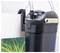 Un filtre à aquarium en canister noir fixé sur le côté d'un réservoir de poissons, avec des tubes pour la filtration de l'eau. Eau claire avec des plantes vertes à l'intérieur de l'aquarium.