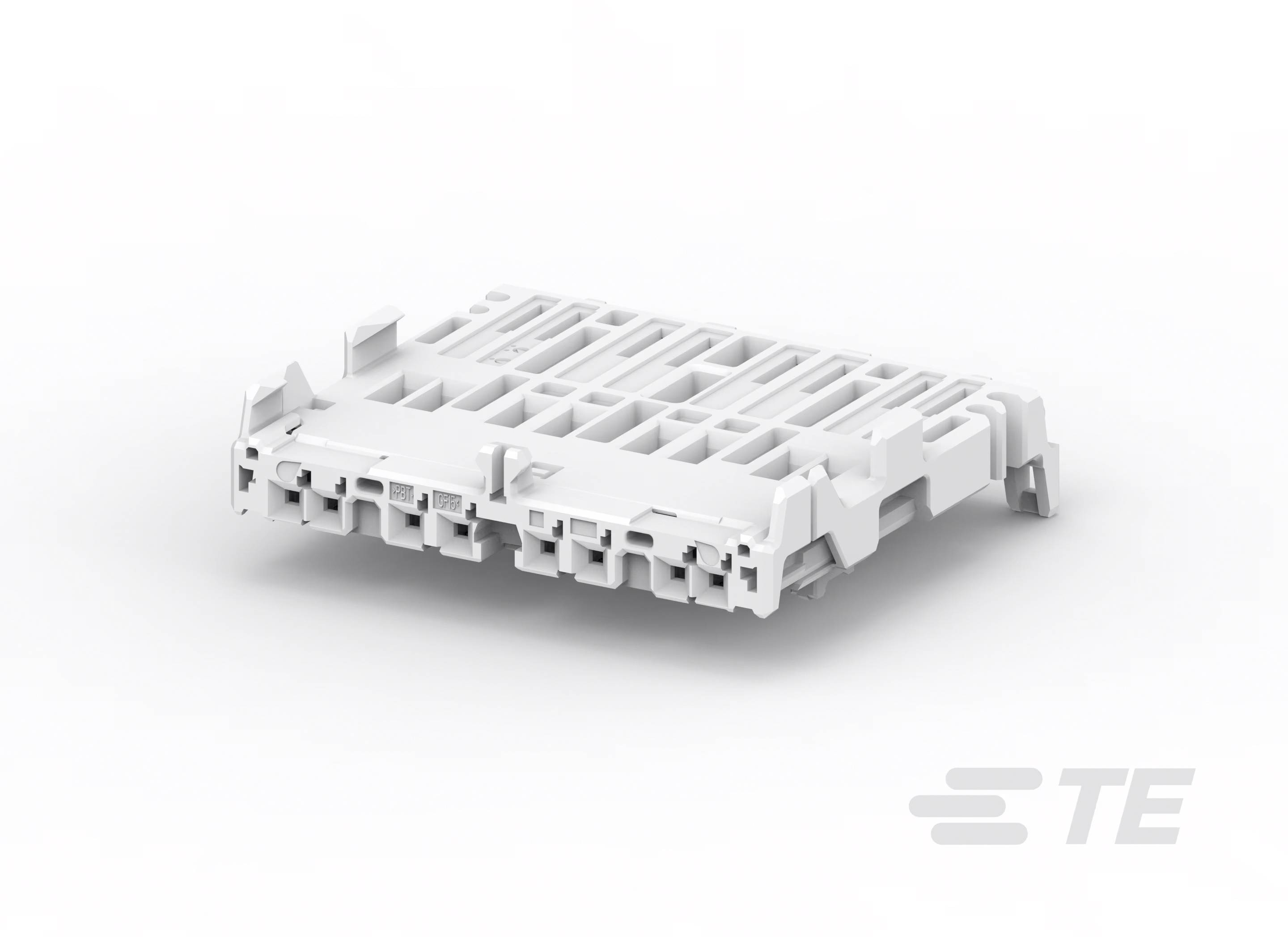 Un composant en plastique blanc avec des ouvertures rectangulaires et des connexions, utilisé pour les connexions électriques. Logo 'TE' en bas à droite.