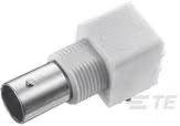 Un adaptateur blanc de forme carrée avec un connecteur métallique rond, utilisé pour des connexions électroniques ou de câbles.