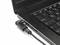 Un ordinateur portable noir avec un câble de chargement branché sur le côté gauche, gros plan sur le clavier et le port de connexion.