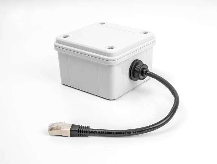 Un boîtier électrique gris rectangulaire avec un câble Ethernet connecté, utilisé pour la connexion réseau.
