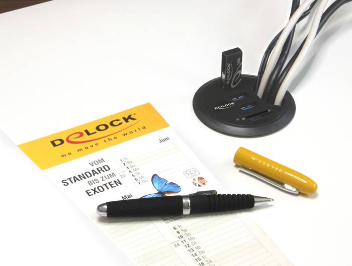 Une feuille de calendrier portant le titre « Du standard aux exotiques » est posée à côté d'un stylo, d'une station de charge USB et de plusieurs câbles.