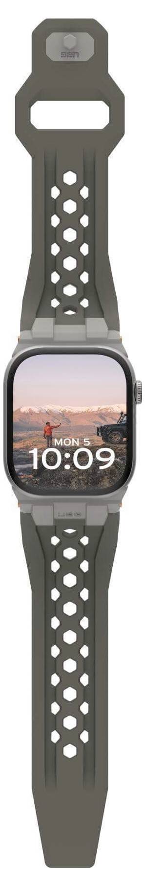 Une montre connectée avec un bracelet perforé affiche sur son écran l'heure 10:09 et une image de coucher de soleil sur la mer.