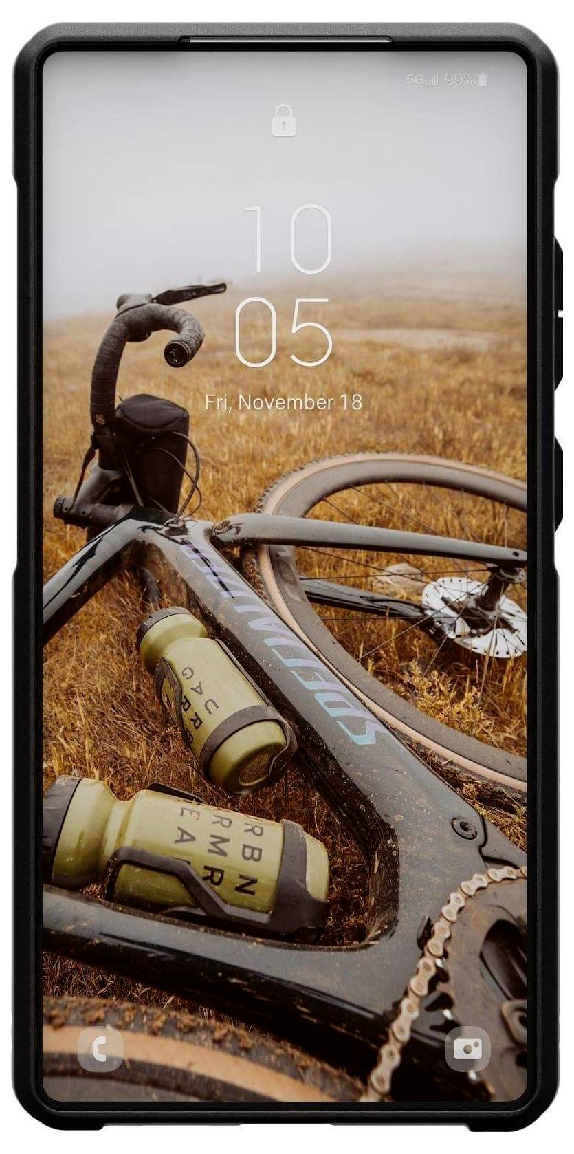 Un vélo est posé dans un champ d'automne ; deux gourdes sont fixées sur le cadre. L'écran du smartphone affiche 'Ven., 18 novembre, 10:05'.