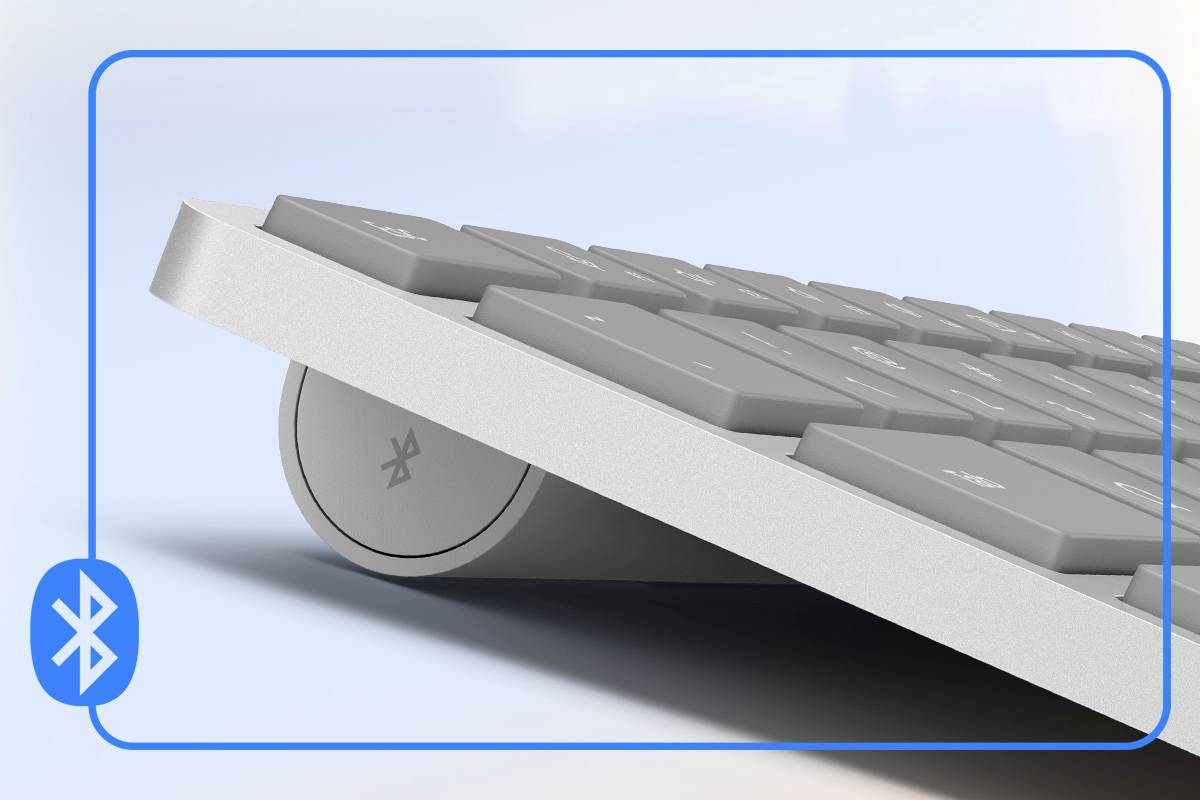 Un clavier sans fil argenté avec connexion Bluetooth, incliné sur le côté, avec des touches visibles et le logo Bluetooth sur le côté.