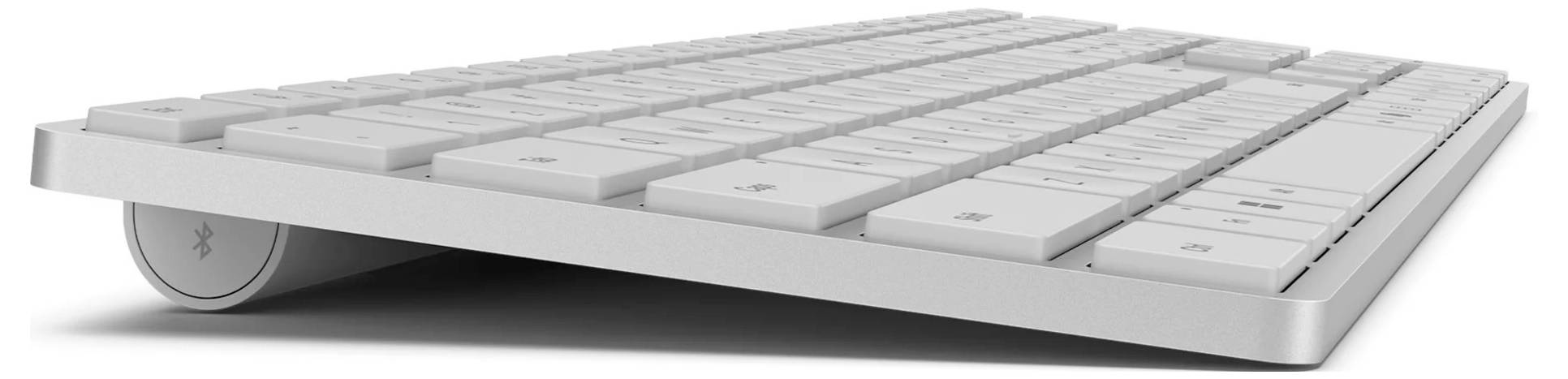 Un clavier argenté sans fil, vu de profil. Il est fin et arbore un design minimaliste.