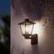 Un réverbère lumineux est accroché au mur, illuminant les alentours au crépuscule avec une lumière douce et chaleureuse.