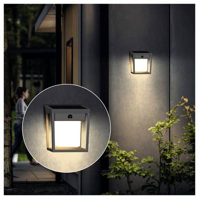 Lanterne murale extérieure allumée sur la façade d'une maison la nuit, avec un gros plan circulaire inséré du luminaire.